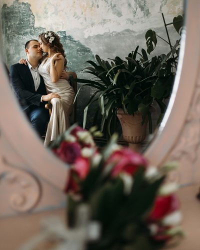 The beautiful bride and groom embracing in the room and sitting on the sofa