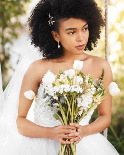 Shot of a happy and beautiful young bride holding a bouquet of flowers while posing outdoors on her wedding day.